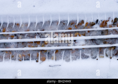 Car tyre print in softening melting snow on a gravel road. Stock Photo