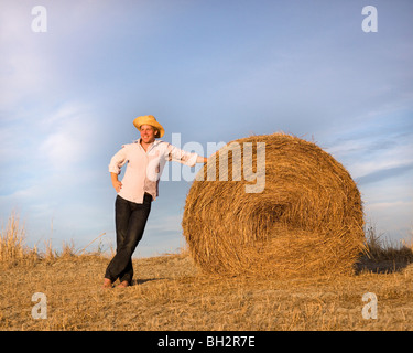 man standing by hay bale Stock Photo