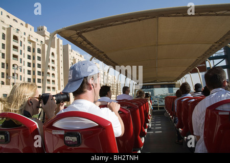 Dubai UAE Passengers on top deck Big Bus Company bus travelling at Jumeirah area listening to commentary through ear phones Stock Photo