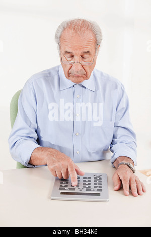 Senior typing on a huge calculator Stock Photo