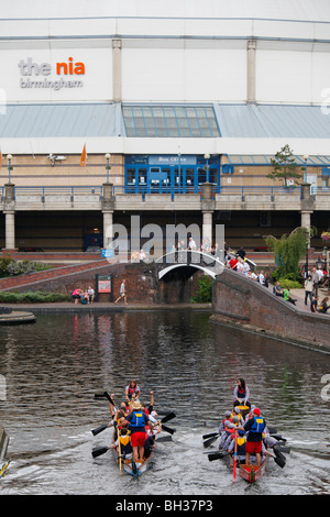 Dragon boat racing in Brindleyplace, Birmingham, showing the National Indoor Arena. Stock Photo