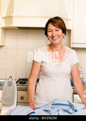 Woman ironing in her kitchen Stock Photo