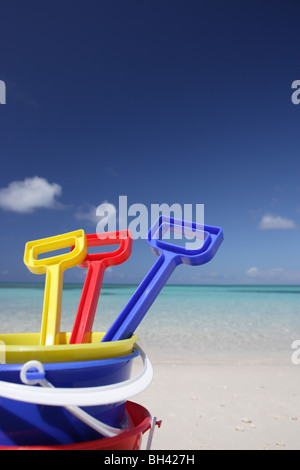 Three children's toy buckets and spades on a deserted tropical beach Stock Photo