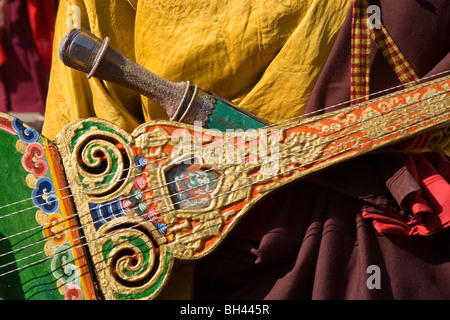 his ancient Bhutanese guitar provides accompanyment along with horns cymbals and drums to dancers and singers Bhutan Asia Stock Photo