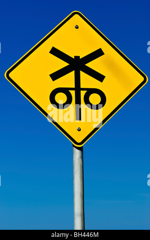 A railway crossing road sign isolated on a graduated blue background. Stock Photo