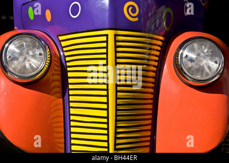 Close up of the front of an older model truck with Orange yellow and purple colors painted on the fenders radiator and hood
