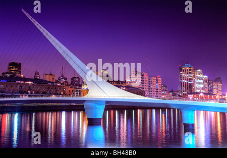 Bridge of the Woman view at dusk, with city silhouette at background and water reflections. Puerto Madero, Buenos Aires Stock Photo