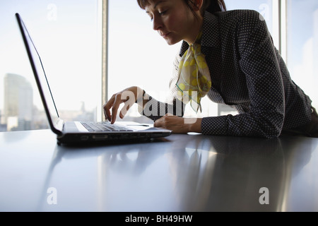 A businesswoman using a laptop computer on an office desk with a serious expression Stock Photo