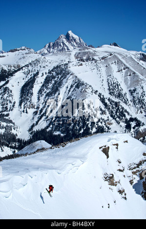 A man skiing a steep slope with the Grand Teton in the background near Jackson Hole, Wyoming. Stock Photo
