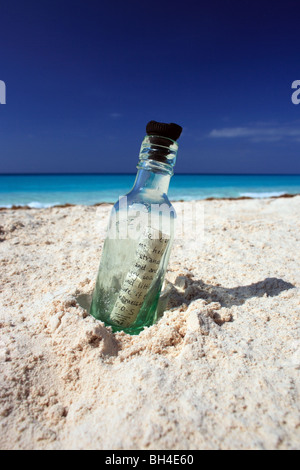 A message in a bottle in the sand on a deserted tropical beach Stock Photo