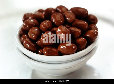chocolate covered peanuts in a small white bowl Stock Photo