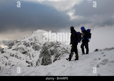 Two male walkers on the summit of Stob Coire Creach, loch restil and Beinn Luibhean in the background. Arrochar alps Scotland UK Stock Photo