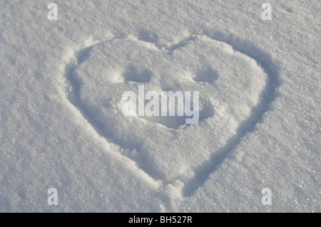 Heart-shaped smiley drawn in snow.