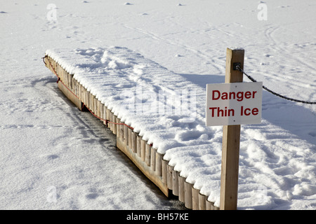 danger thin ice sign on a wooden jetty leading to a frozen lake centre parcs penrith uk Stock Photo