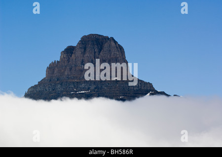 Mt. Reynolds on Logan Pass protrudes above a layer of thick clouds Stock Photo