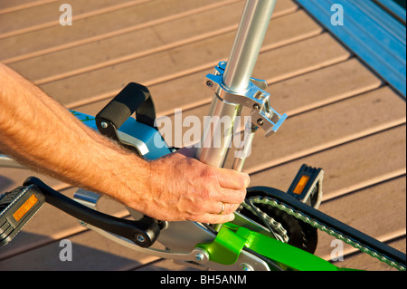 Man unfolding a Mobiky folding bicycle on a landing stage with yachts Stock Photo