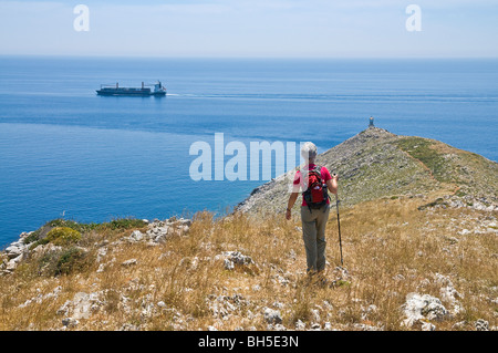 A lone walker on a ridge descending to the Lighthouse at the tip of Cape Tenaro in the deep Mani, Peloponnese, Greece Stock Photo