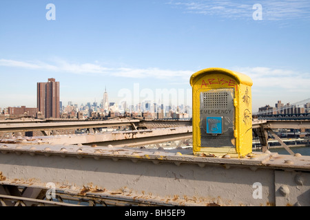 A police emergency phone box located on the Brooklyn Bridge in New York. The Manhattan skyline is visible in the background Stock Photo