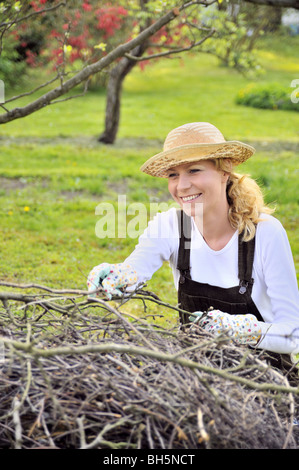 Young woman cleaning tree limbs in orchard Stock Photo