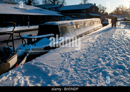 Footprints in the snow beside frozen narrow boats on the Llangollen Canal at Ellesmere, Shropshire, England Stock Photo