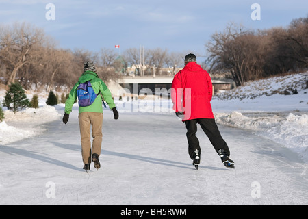 Couple ice skating on the frozen Assiniboine River Trail, Winnipeg, Manitoba, Canada.