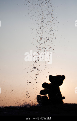 Teddy bear catching water drops silhouette Stock Photo
