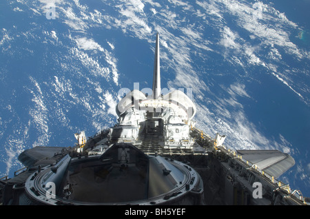 A partial view of Space Shuttle Atlantis backdropped by a blue and ...