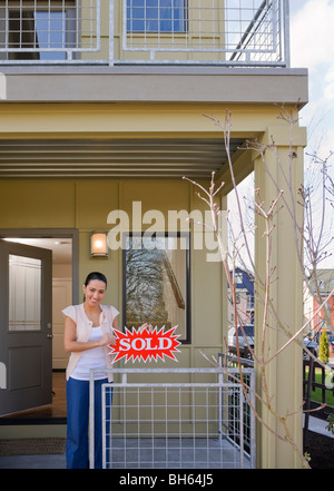 woman on front porch with sold sign Stock Photo