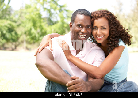 Portrait Of Young Couple Sitting In Park Stock Photo