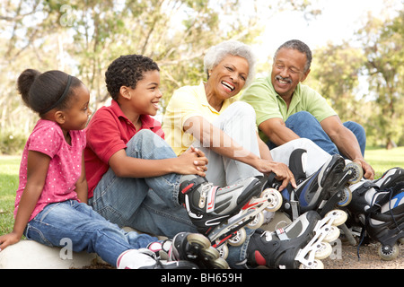 Grandparent With Grandchildren Putting On In Line Skates In Park Stock Photo