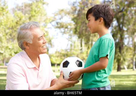 Grandfather And grandson In Park With Football Stock Photo