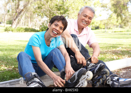 Senior Couple Putting On In Line Skates In Park Stock Photo
