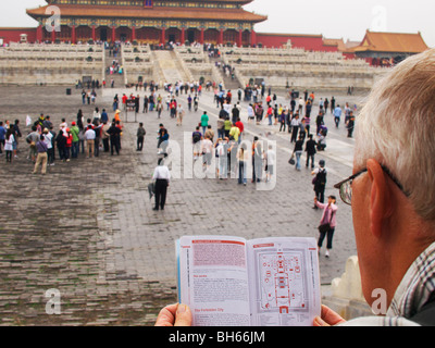Western Tourist studies guide book, whilst standing in the grounds of the forbidden city, Beijing Stock Photo