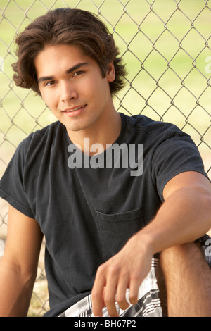 Teenage Boy Sitting In Playground Stock Photo