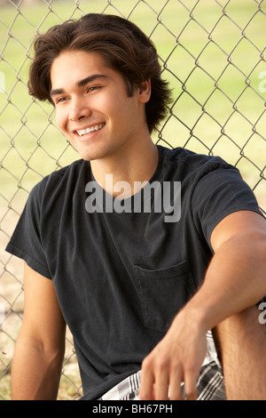 Teenage Boy Sitting In Playground Stock Photo