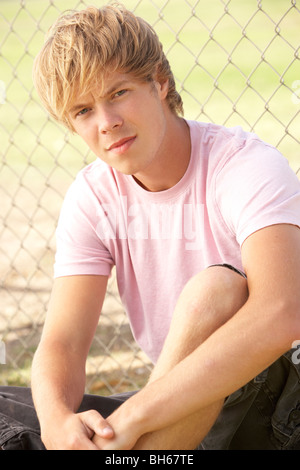 Teenage Boy Sitting In Playground Stock Photo