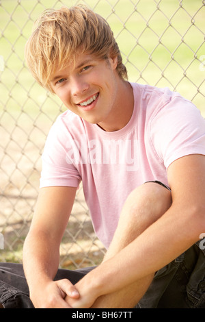 Teenage Boy Sitting In Playground Stock Photo