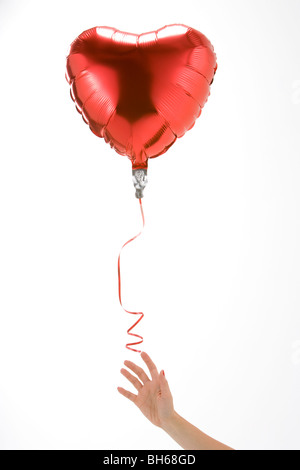 Hand Letting Go Of Heart Shaped Balloon Stock Photo