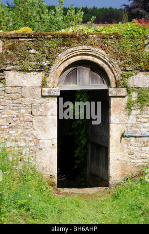 A Norman door in a wall leading to the churchyard from the manor house. Cotswolds UK. Stock Photo