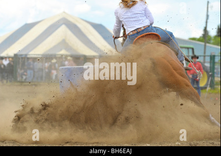A rodeo competitor competing in a barrel racing event under dusty arena conditions. Stock Photo