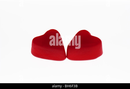 This photo is two red heart gummy candies touching together on a white background.  Perfect to represent Valentine's Day. Stock Photo