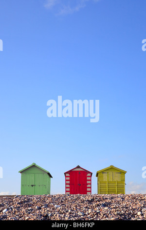 Three colourful beach huts against a bright blue sky, framed to allow copy space in the upper part of the image. Stock Photo