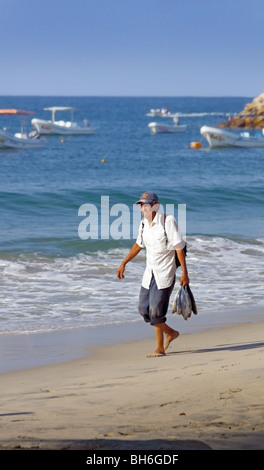 Escondido Oaxaca Mexico, beach with local man walking with fish Stock Photo