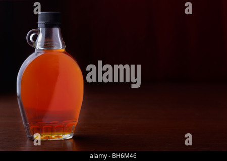 A bottle of maple syrup sits on a table Stock Photo