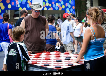 A family play checkers on a giant board at the Just for laughs Festival street party in Montreal Stock Photo