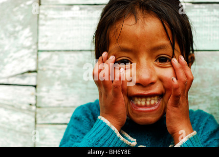 Ecuador, Latacunga, close-up portrait of a messy girl with a toothy smile with head in hands Stock Photo