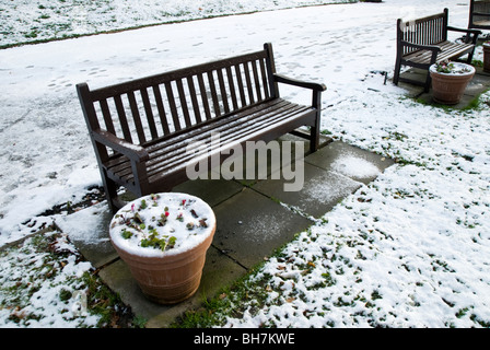 Snow covered park benches and flower pots in a London Park Stock Photo