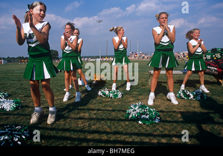 Young cheerleaders jump off the ground together during a Saturday morning High School football match in Mount Joy, Pennsylvania. Stock Photo