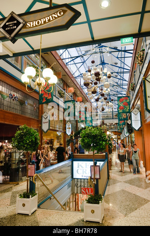 Brisbane Arcade Shopping Mall Interior Brisbane Australia | BRISBANE, Australia — Shoppers pass beneath decorative banners in the Brisbane Arcade, a heritage-listed shopping thoroughfare linking Queen Street and Adelaide Street. Designed by architect Richard Gailey and opened in 1923, the arcade retains its original steel-framed glass roof, stained-glass galleries and two-level gallery layout, characteristic of Edwardian-era arcade design. Stock Photo