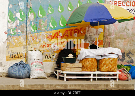 Ecuador, Otavalo, side view of a man selling vegetables under an umbrella on a sidewalk Stock Photo